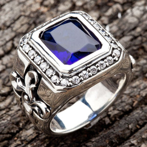 Ein schwerer Siegelring aus Silber mit einem blauen Stein und einer gravierten Lilie (Fleur-de-Lis) oder einem Blumenkreuz auf der Ringschiene