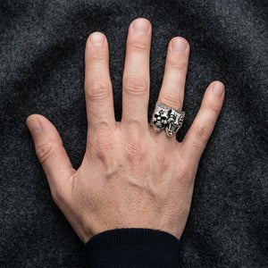 Joker and skull sterling silver ring worn on a hand against dark wool