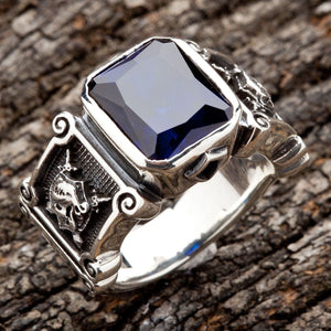 Ein handgefertigter Ritterschild-Ring mit einem tiefblauen Edelstein und geprägten Schilden im römischen Stil mit stilisierten Kreuzen