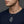Small sterling silver knuckle duster pendant with a 2 mm silver chain threaded through its top hole, worn by a male model