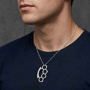 Small sterling silver knuckle duster pendant with a 2 mm silver chain threaded through its top hole, worn by a male model
