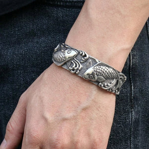 Brazalete abierto de plata de ley con pez koi puesto en la muñeca de un adulto