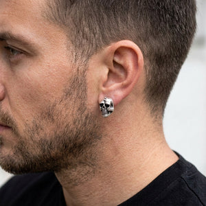 Grande puce d'oreille en argent en forme de tête de mort portée à l'oreille d'un mannequin homme