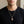 Lucha libre mask pendant worn over a black shirt; chain shown for styling