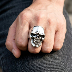 Polierter Totenkopfring aus Silber, getragen am Mittelfinger einer natürlich geschlossenen Faust