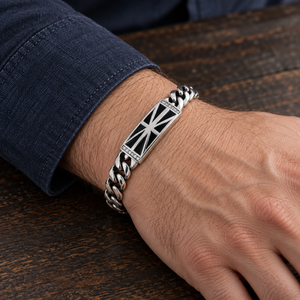 Black Union Jack Sterling Silver ID Bracelet with its black flag plate on an adult wrist beside a navy cuff.