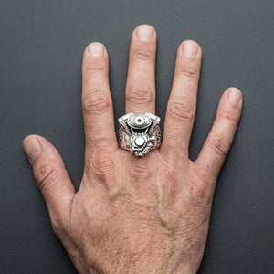 Sterling silver V-twin motorcycle engine ring worn on a full open hand, engine face and shield shoulders visible