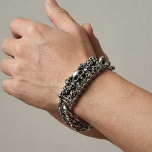 Multi-skull ID silver bracelet worn on a wrist