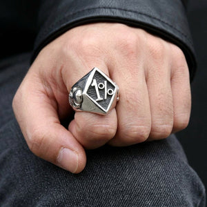 1%-ring i sterlingsølv med rombeformet front og ringskulder med hodeskalle, båret på en lett bøyd hånd over mørk denim.