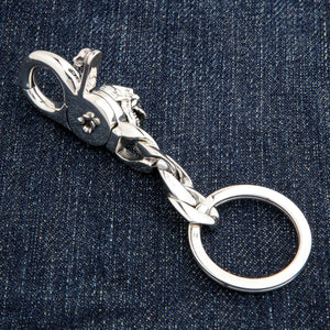 Nøkkelring i sterlingsølv med hodeskalle med åpen kjeve som viser baksiden av hodeskallen og låsen mot denim.