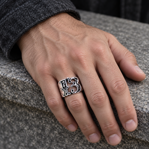 Openwork Gothic 13 Sterling Silver Ring on an adult hand resting on grey stone.