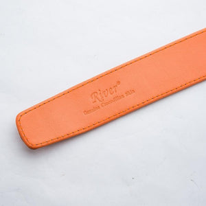 Ratchet-belte med oransje krokodilleinnlegg som viser preget skrift i det glatte skinnfôret.