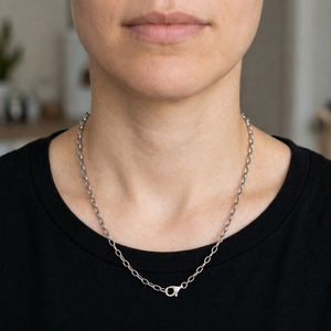 Collier chaîne maille forçat à maillons ovales en argent sterling 925 porté par une femme vêtue d'un haut noir à col rond