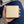 Pearl-white stingray bifold with tan edging held over a navy-clothed lap.