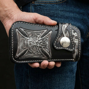 Phantom Skull & Iron Cross Leather Biker Wallet, held closed at hip level with the decorated front visible