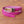 Pink crocodile leather women's belt with silver buckle coiled on wooden surface