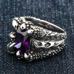 Örnklo-ring med lila kubisk zirkonia i sterlingsilver. Fjällmönstrade silverskuldror möter den höga klofattningen.