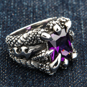 Örnklo-ring med lila kubisk zirkonia i sterlingsilver. Fyra silverklor griper en fasetterad lila CZ över en mönstrad ringskena.