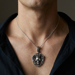Crowned skull silver pendant with clear eye stones, shown against a male neck and chest