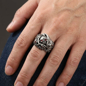 Red CZ Inferno Skull Sterling Silver Ring, worn on one middle finger in a natural hand close-up