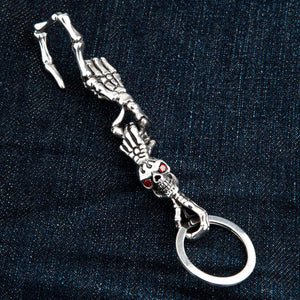Red-Eye Skeleton Skull Sterling Silver Keychain showing all skeletal sections laid diagonally on denim.