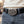 Oval silver skull-pile buckle with red eye accents worn on a styling belt over grey jeans.