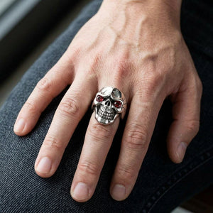 Red CZ Eye Sterling Silver Skull Ring, worn on one middle finger in a natural hand close-up