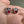 Pendientes de botón de plata de ley con ojo rojo, par con ojo rojo y engaste de garras en ángulo en una mano