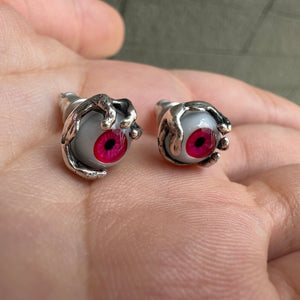 Pendientes de botón de plata de ley con ojo rojo, par con ojo rojo y engaste de garras en ángulo en una mano
