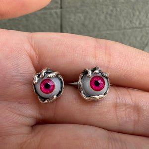 Pendientes de botón de plata de ley con ojo rojo, par de pendientes con ojo rojo sobre una mano abierta