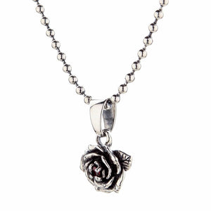 Ciondolo rosa con granato in argento sterling. L'inclinazione opposta rivela la profondità del fiore e la pietra rossa al suo centro.