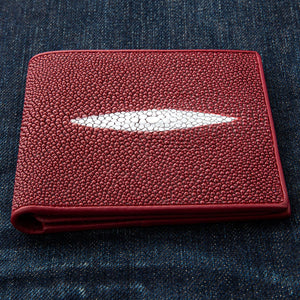 Red Pearl Stingray Bifold Wallet showing pale pearl stripe across the red front, resting on denim.