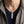 Pendente a piuma con granato rodolite su catena d'ambientazione sopra top blu navy e camicia grigia.