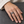 Openwork Wave Weave Sterling Silver Band Ring on a hand resting on grey stone beside a pale linen cuff.