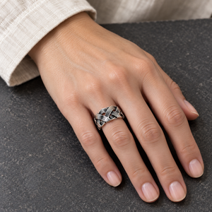 Openwork Wave Weave Sterling Silver Band Ring on a hand resting on grey stone beside a pale linen cuff.