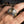 Rutilated quartz tri-metal silver ring worn on a hand, showing the faceted stone and brass money-bag detail against a blurred workshop background