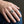 Anillo de banda Santa Muerte de plata esterlina con granate, usado en un dedo medio en un primer plano de mano natural