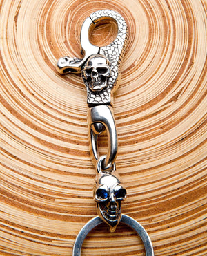 Nyckelring i sterlingsilver med dödskalle med blå safirögon, detalj av främre dödskallelås och dödskalle med blå ögon