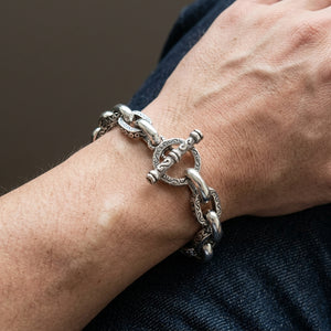 Bracciale toggle pesante in argento sterling con volute tribali, indossato naturalmente al polso con la chiusura visibile