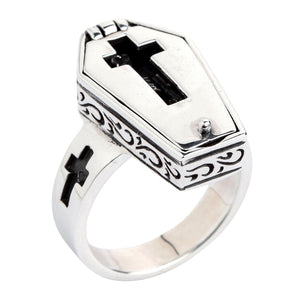 Angled closed view showing the coffin lid, dark scrollwork and a cross opening in the silver band.