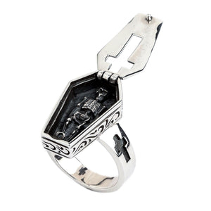 Three-quarter view into the open coffin ring with the sculpted skeleton against a dark interior.