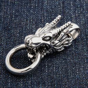 Ciondolo a testa di drago in argento su denim, con anello rotondo sotto la bocca.
