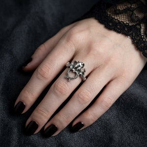 Small sterling silver octopus ring on a pale woman’s hand with black nails and lace cuff