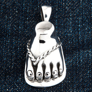 Sandaalvoet-hanger van 925 sterling zilver. Vijf gemodelleerde tenen en het zilveren sandaalbandje worden getoond tegen blauw denim.