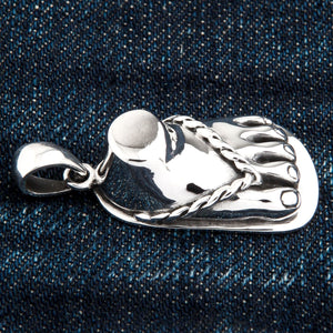 Sandaalvoet-hanger van 925 sterling zilver. De hanger ligt horizontaal op denim en toont het verhoogde bandje en de afgeronde tenen.