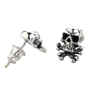 Totenkopf und gekreuzte Knochen Ohrstecker aus Sterlingsilber. Ein Totenkopf zeigt nach vorne, während der andere gedreht ist und seinen Steckerstift sowie den Steckverschluss zeigt.