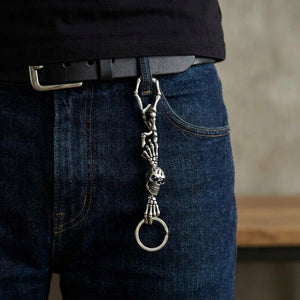Skeleton Bone Sterling Silver Keychain with dark blue gem eyes, clipped to denim
