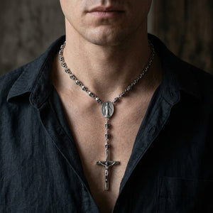 Skull bead silver rosary necklace with oval medallion and crucifix worn over a dark shirt