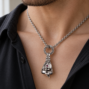 Red-eye skull bell pendant worn on a silver chain threaded through the engraved top ring
