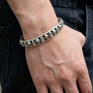 Bracelet manchette tête de mort et os croisés en argent sterling porté autour d'un poignet d'adulte